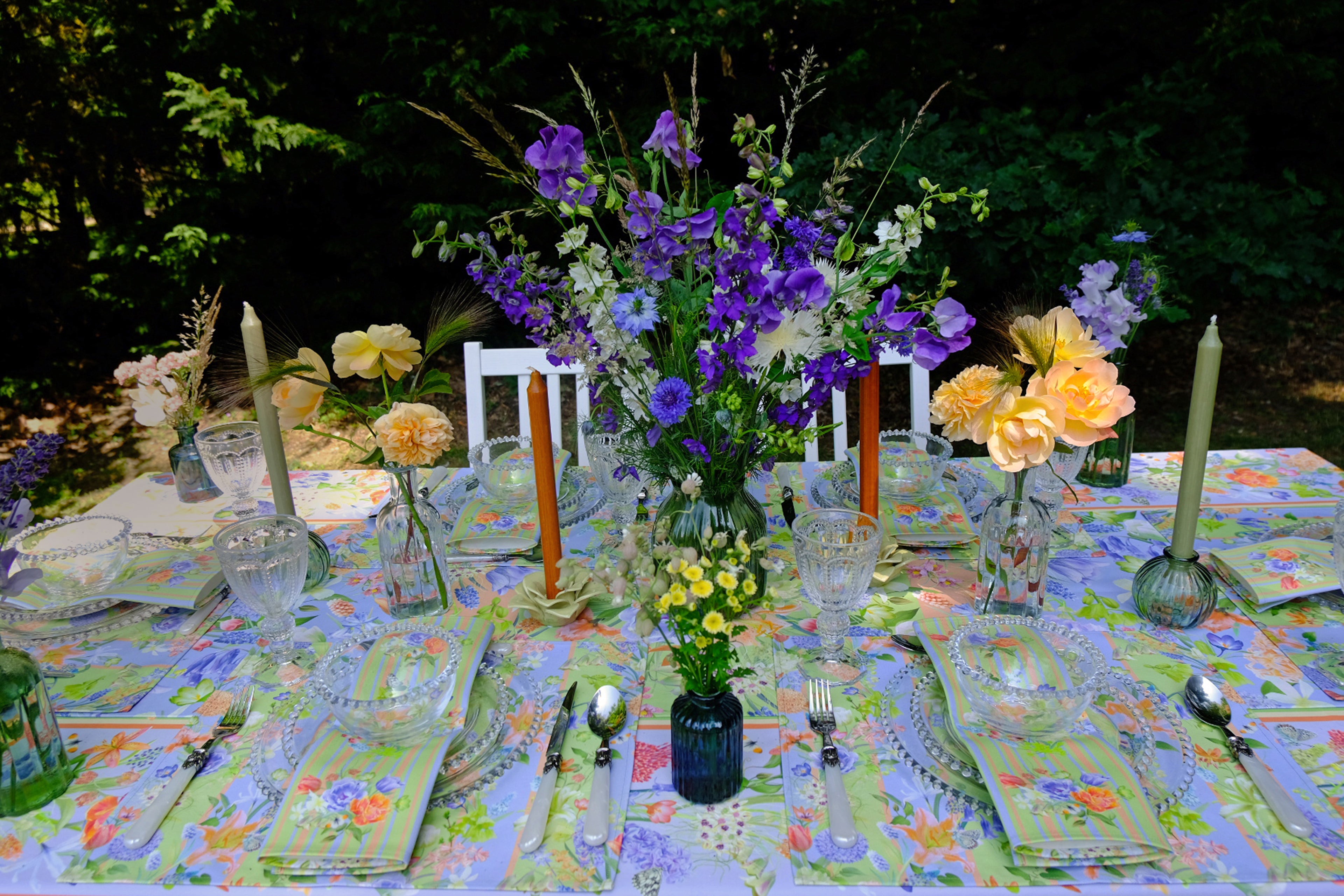 Decorated table with floral centerpieces and place settings outdoors.