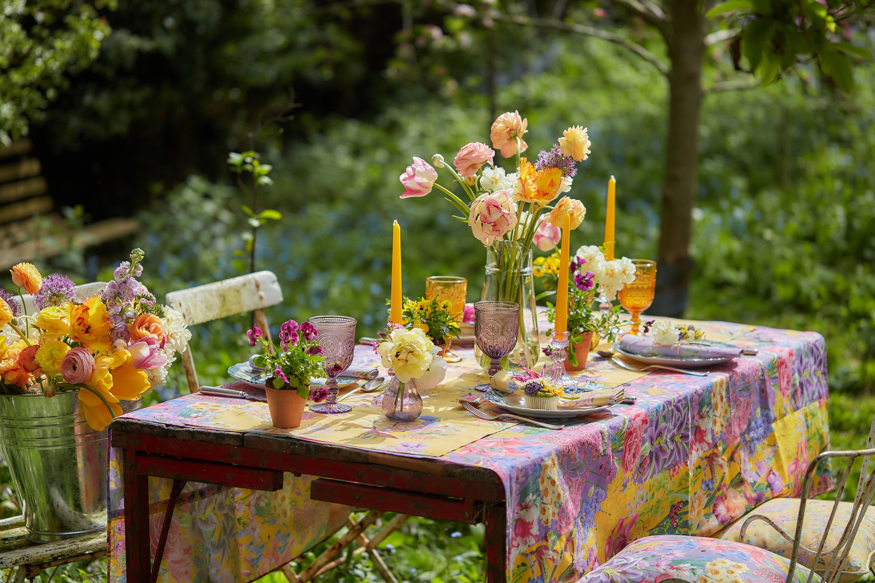 Summer dining tablescape with floral pattern tablecloth, napkins and cushions in organic cotton.
