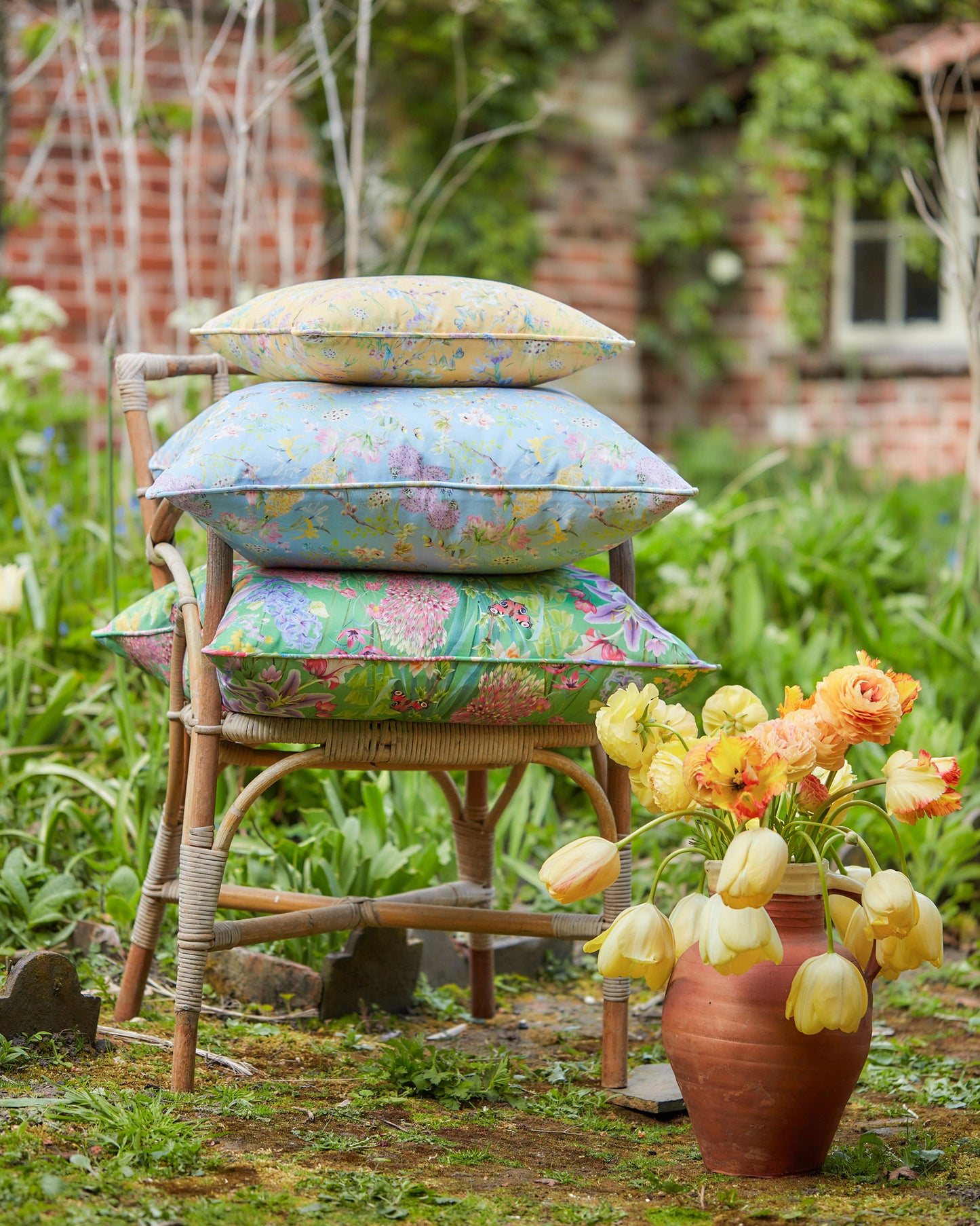 Outdoor garden styling featuring cushions made from Hopeful Beginnings pastel blue botanical fabric surrounded by seasonal flowers.