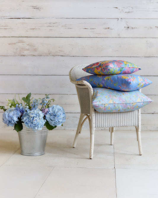 Chair styled with cushions made from Hopeful Beginnings pale blue botanical fabric, showcasing the floral print at furnishing scale.