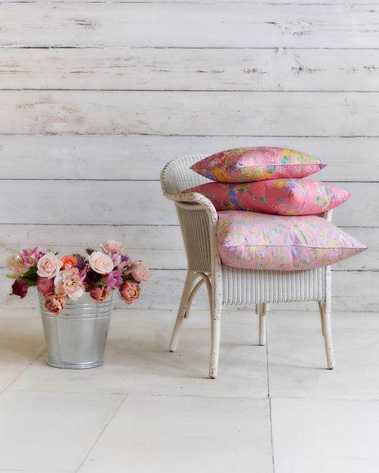 Chair styled with decorative cushions made from Hopeful Beginnings pale pink botanical fabric, showcasing the floral print at furnishing scale.
