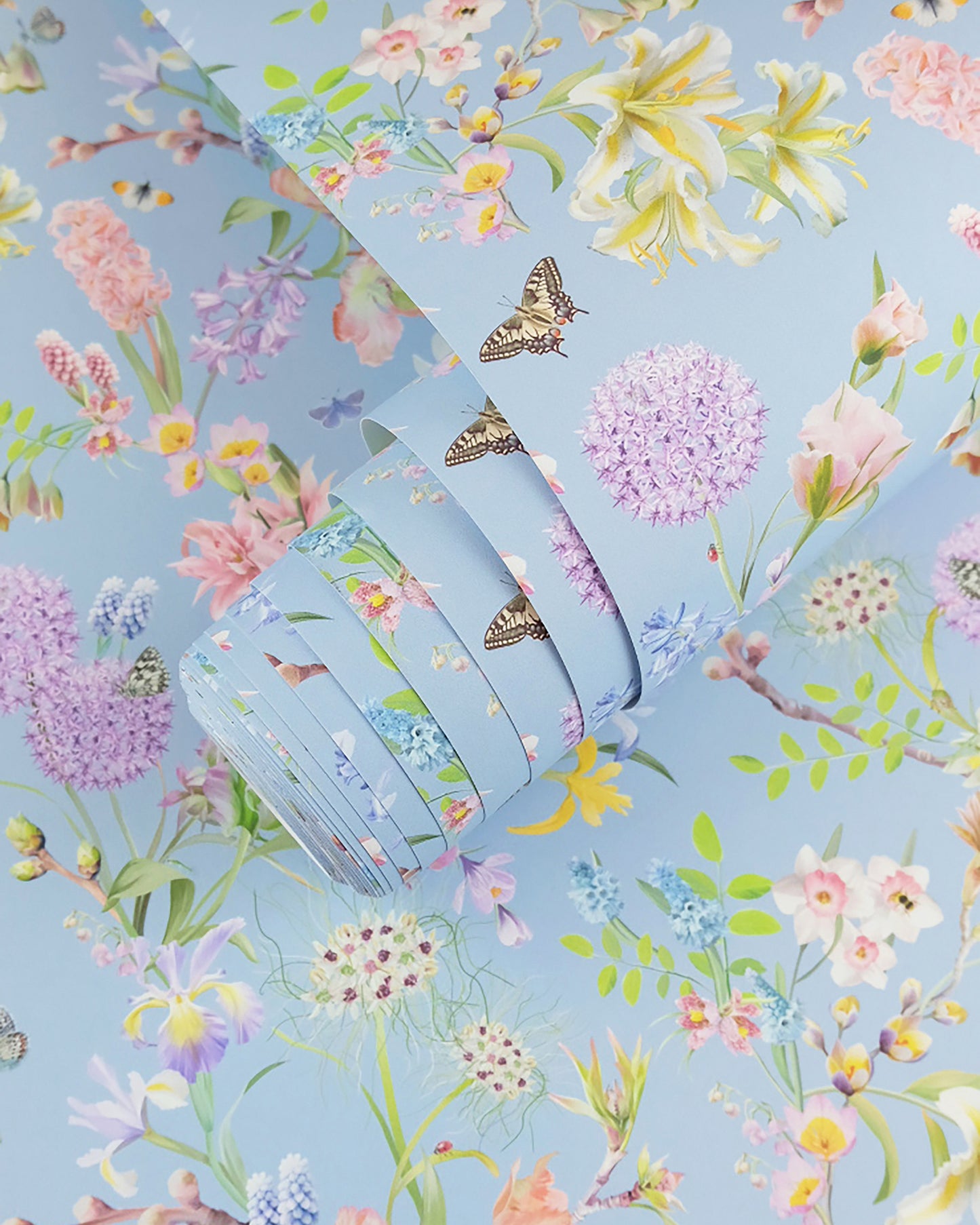 A roll of soft blue neutral wallpaper with a spring botanical print for cottage interior design
