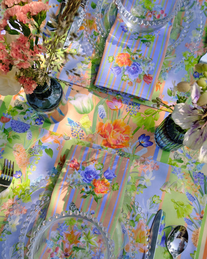 Colourful tablecloth with floral patterns, cutlery, and decorative items on a table.