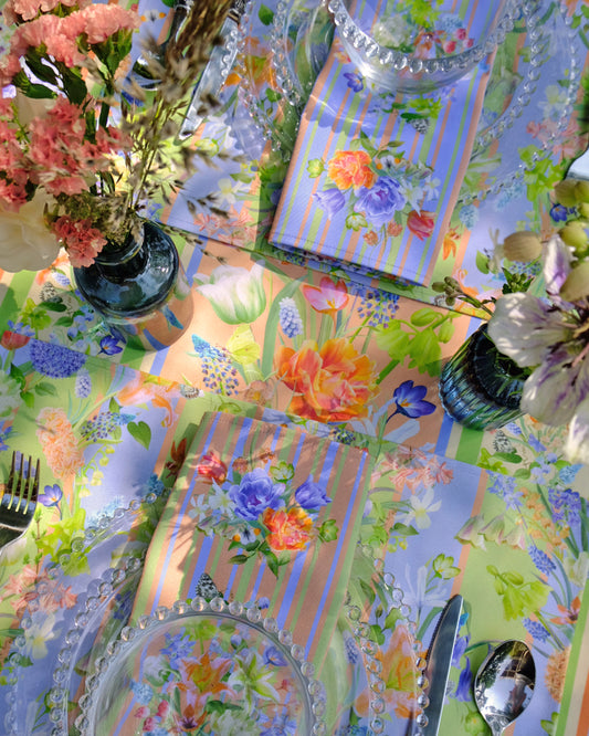 Colourful tablecloth with floral patterns, cutlery, and decorative items on a table.