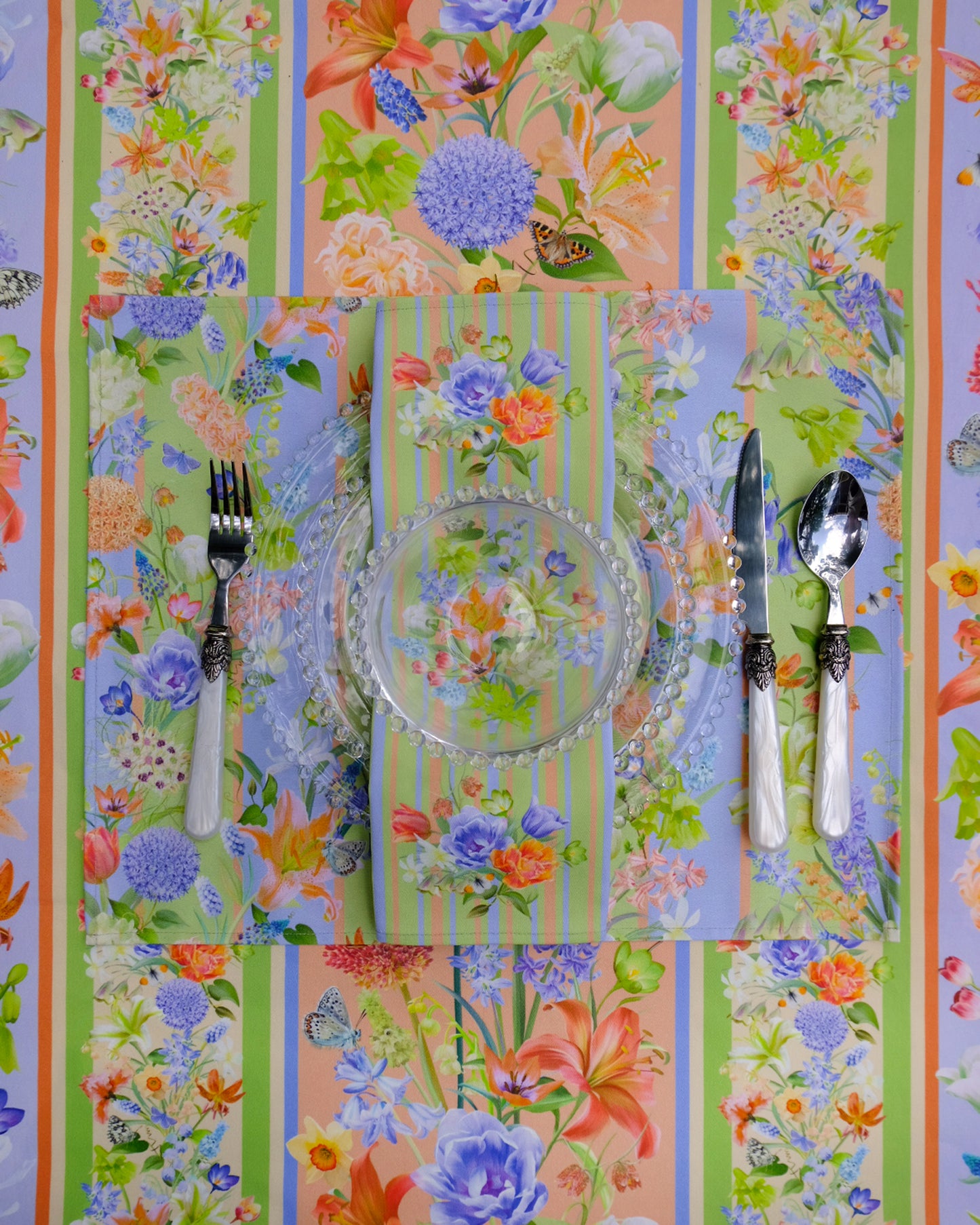 Colourful floral-patterned tablecloth with cutlery on a striped background