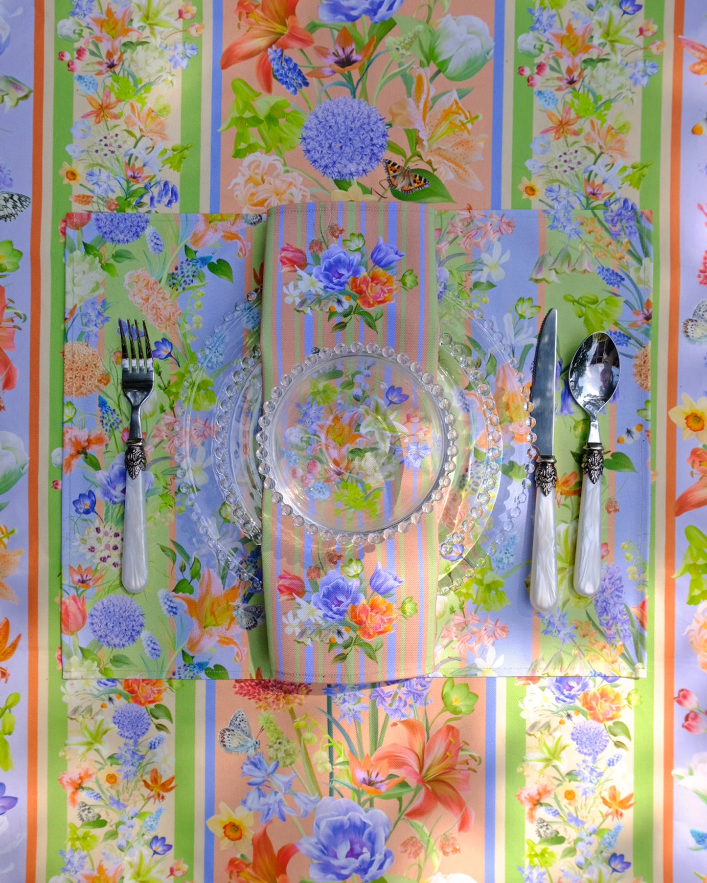 Colourful floral-patterned tablecloth with cutlery on a striped background