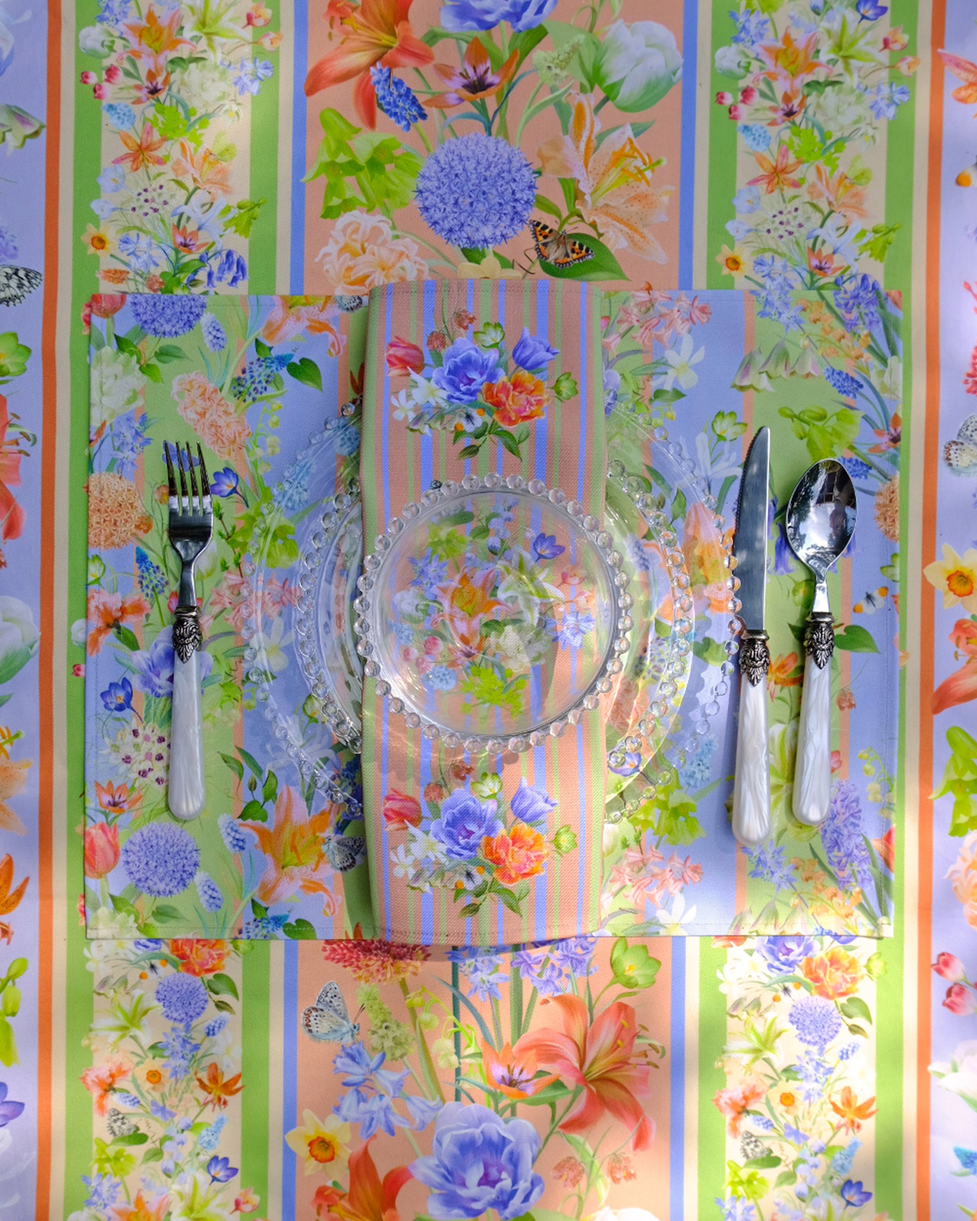Colourful floral-patterned tablecloth with cutlery on a striped background