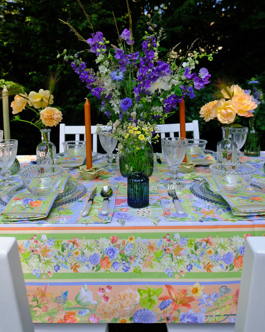 Decorative table setting with flowers, candles, and colorful tablecloth outdoors.