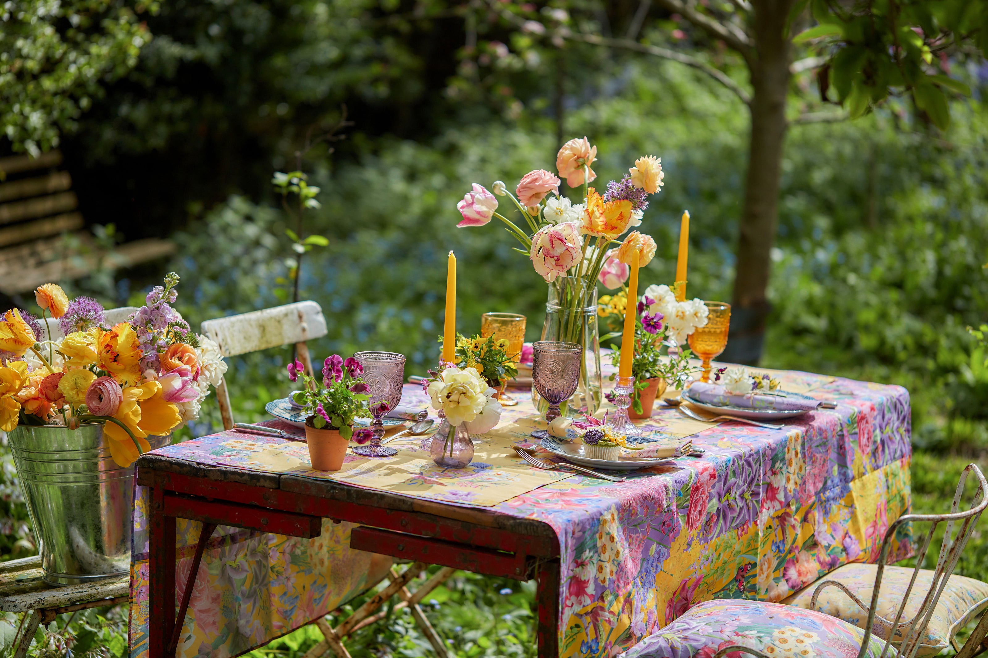 Burst Into Bloom botanical fabric styled on an outdoor dining table with colourful flowers, candles and garden inspired tableware.