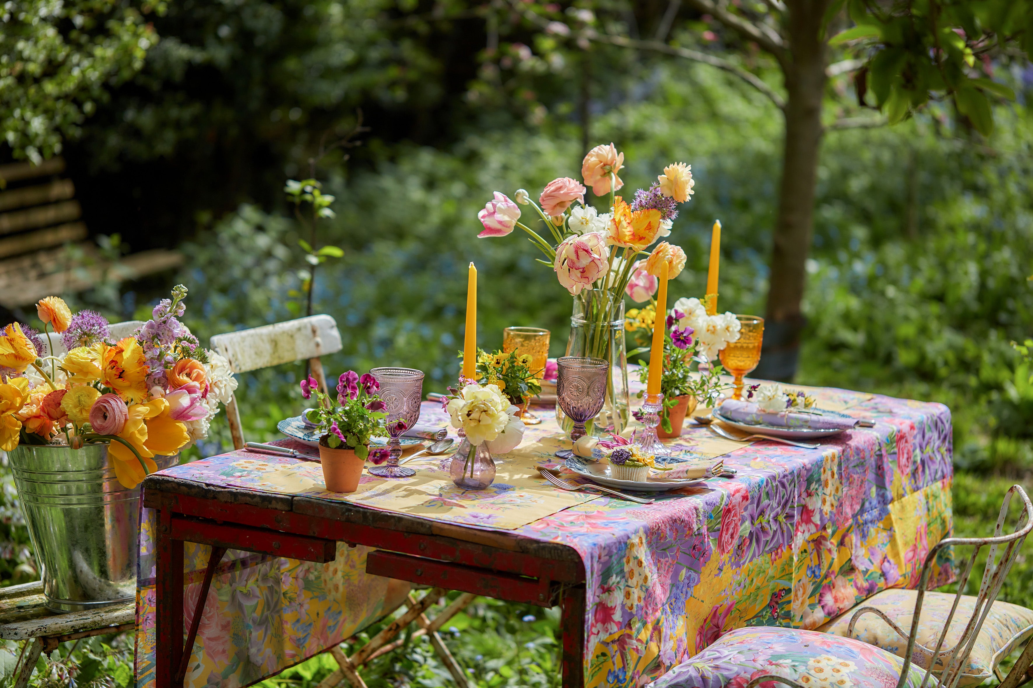 Burst Into Bloom botanical fabric styled on an outdoor dining table with colourful flowers, candles and garden inspired tableware.