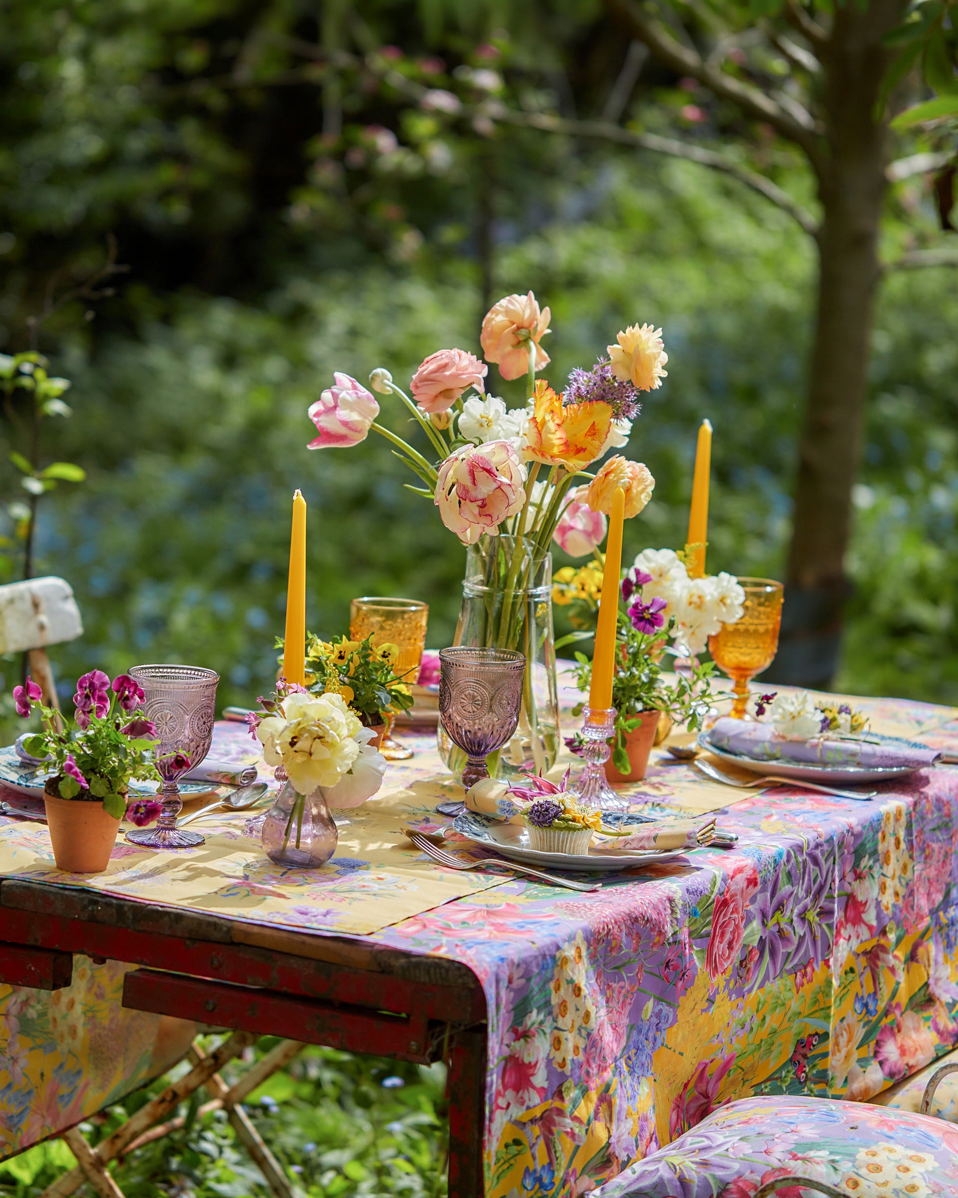 Burst Into Bloom Yellow botanicals floral fabric used as a tablecloth for outdoor dining, featuring colourful spring flowers on a vibrant gold background.