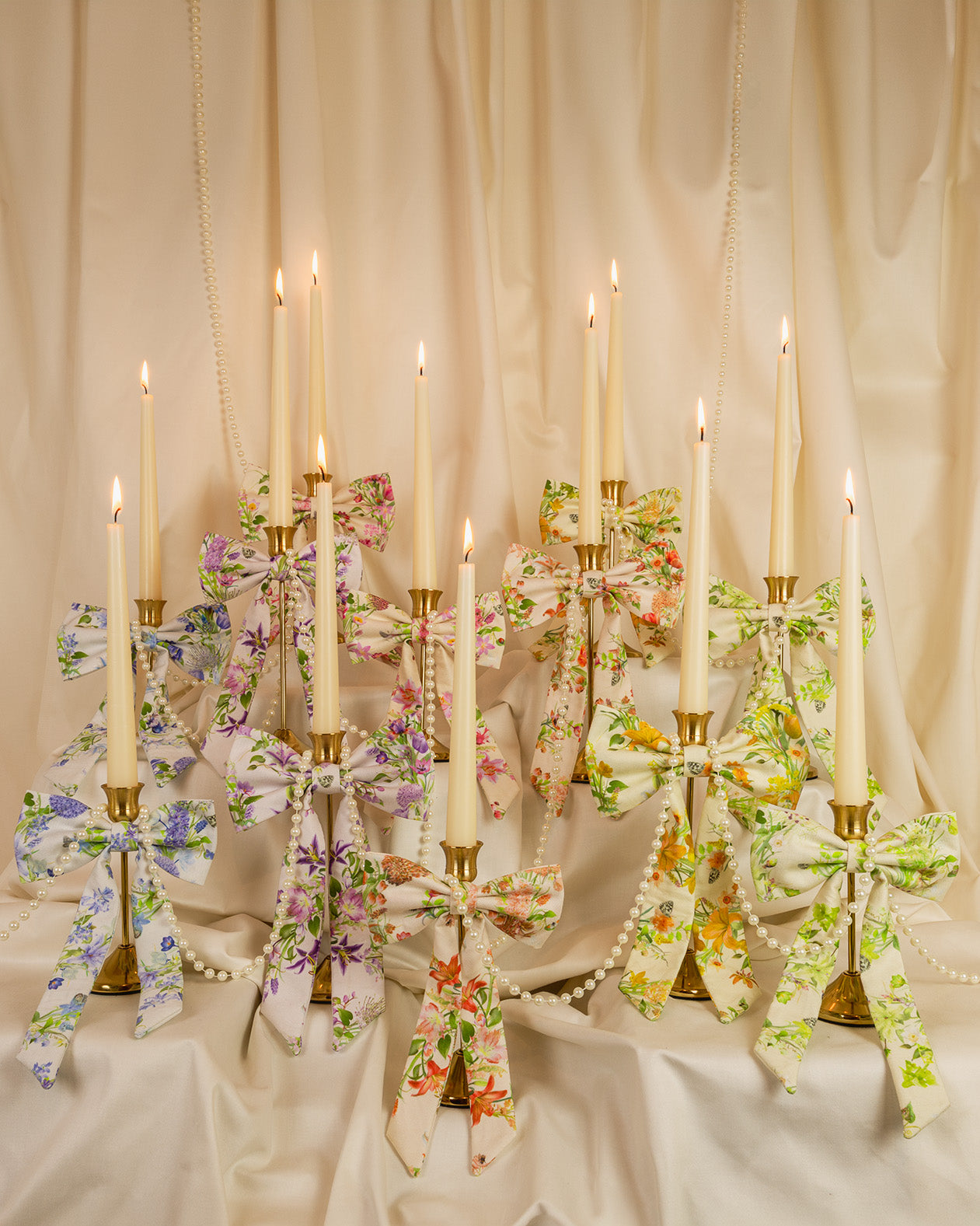 Decorative candle holders with floral ribbons against a beige curtain backdrop