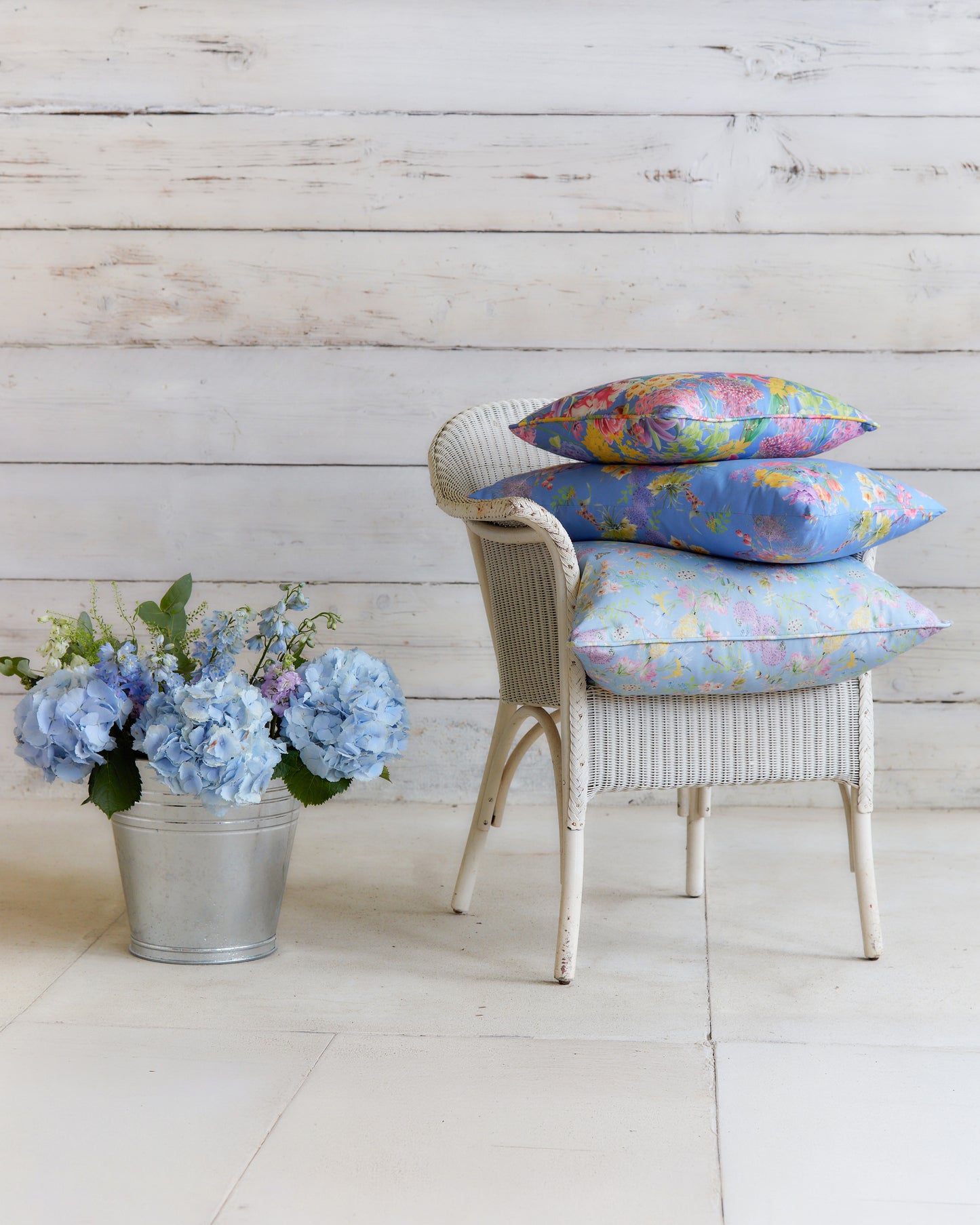 Chair styled with cushions made from Hopeful Beginnings pale blue botanical fabric, showcasing the floral print at furnishing scale.
