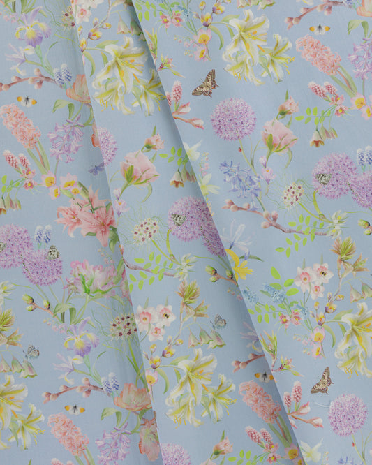 Draped Hopeful Beginnings cotton twill furnishing fabric in pastel blue showing detailed botanical floral pattern.