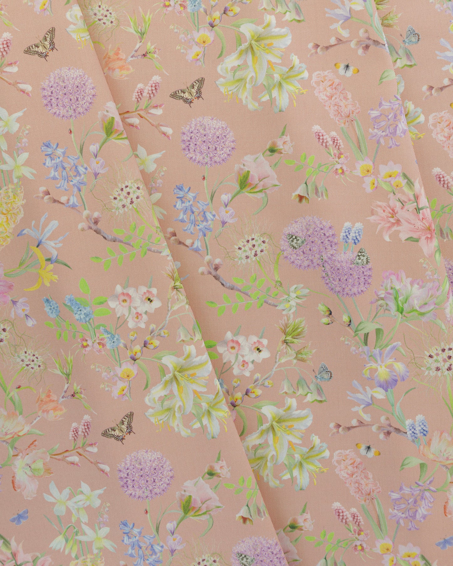 Draped Hopeful Beginnings cotton twill furnishing fabric in pastel peach showing detailed botanical floral pattern.