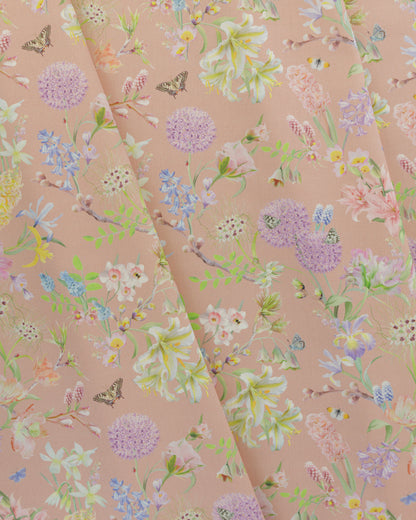 Draped Hopeful Beginnings cotton twill furnishing fabric in pastel peach showing detailed botanical floral pattern.