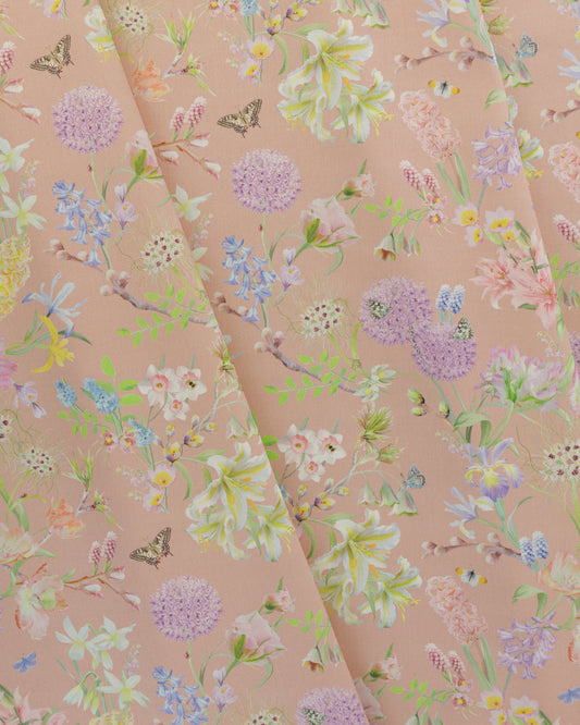 Draped Hopeful Beginnings cotton twill furnishing fabric in pastel peach showing detailed botanical floral pattern.