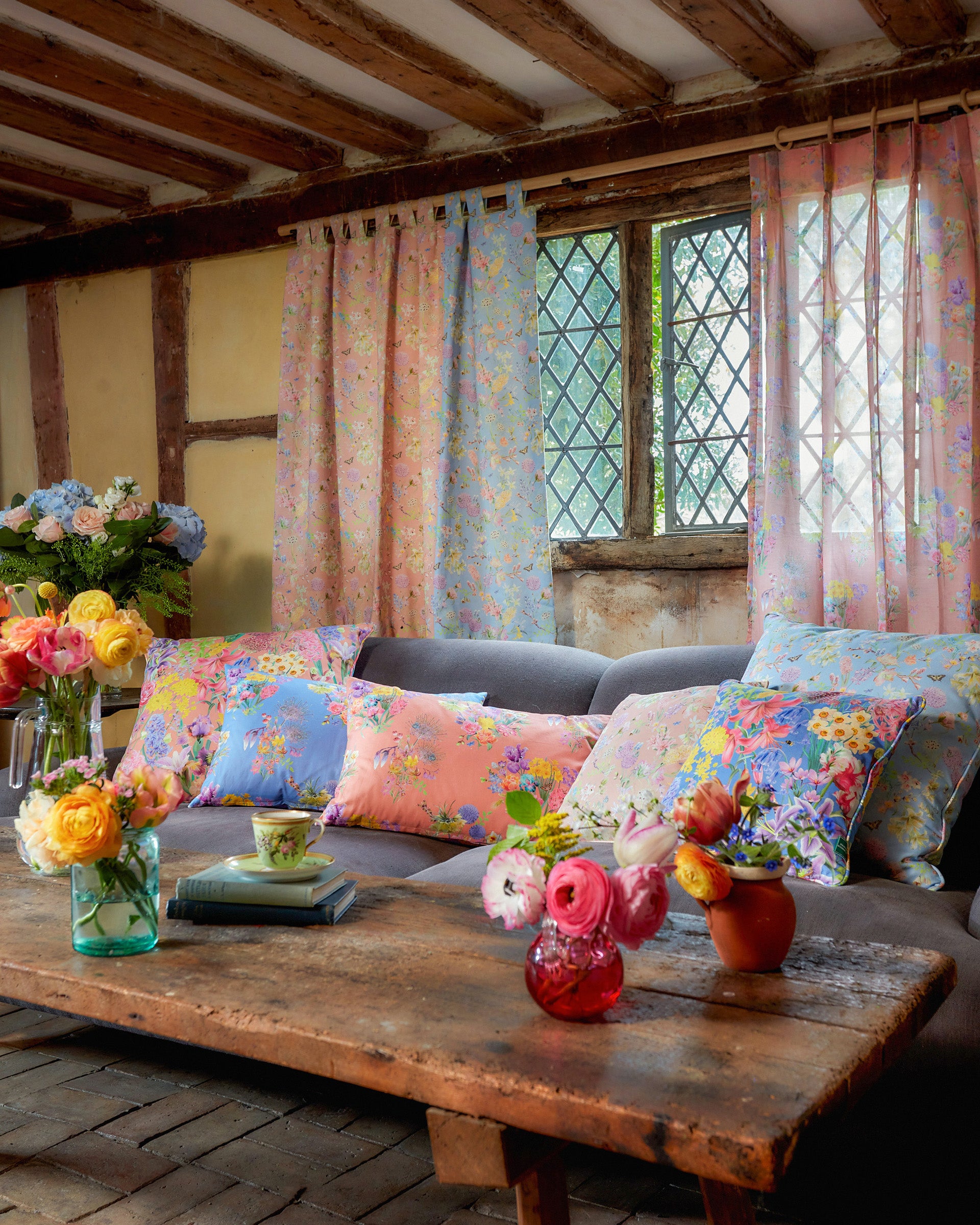 Hopeful Beginnings soft peach floral fabric used for cushions in a cosy country living room with warm wood interiors.