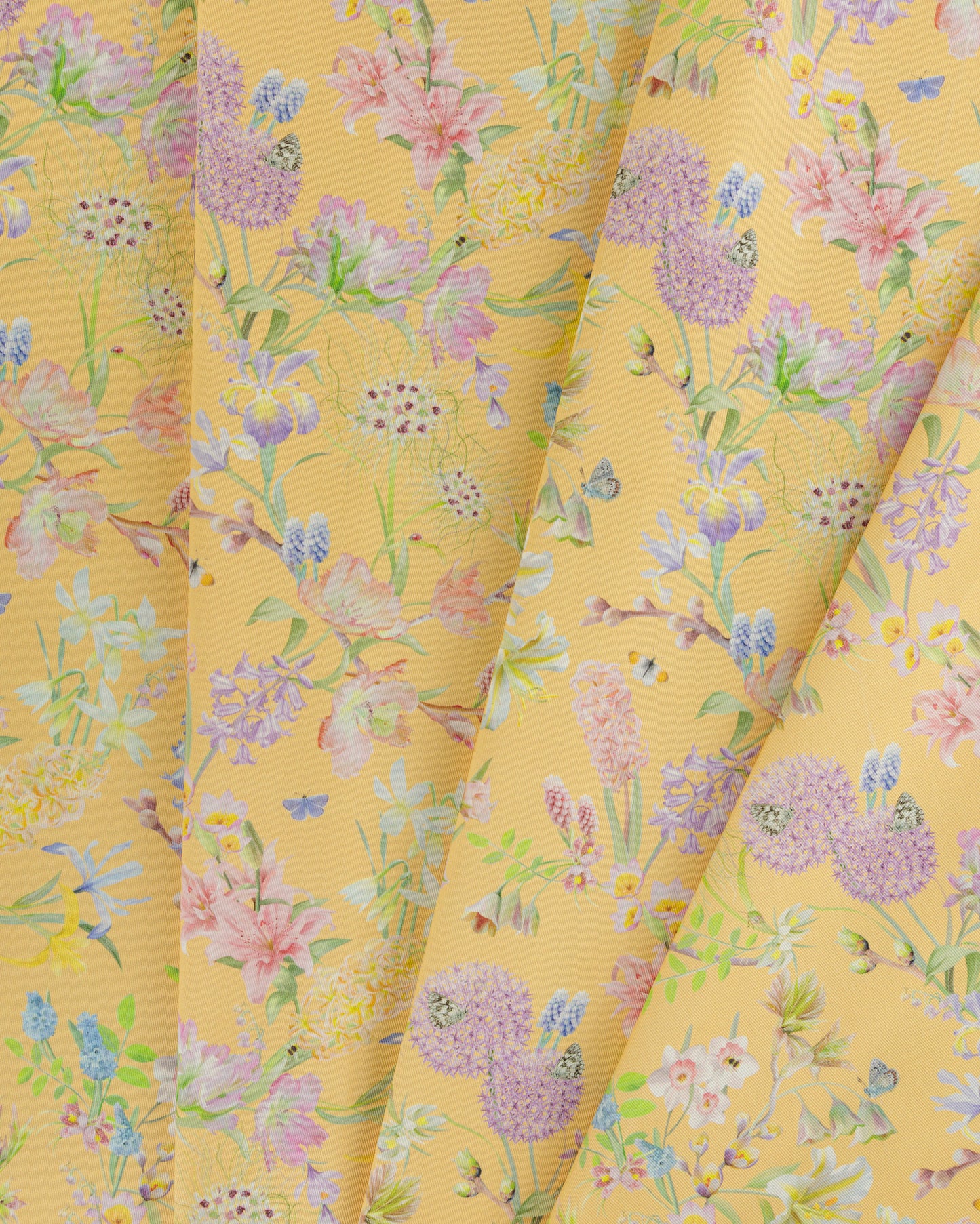 Draped Hopeful Beginnings cotton twill furnishing fabric in yellow showing detailed botanical floral pattern.