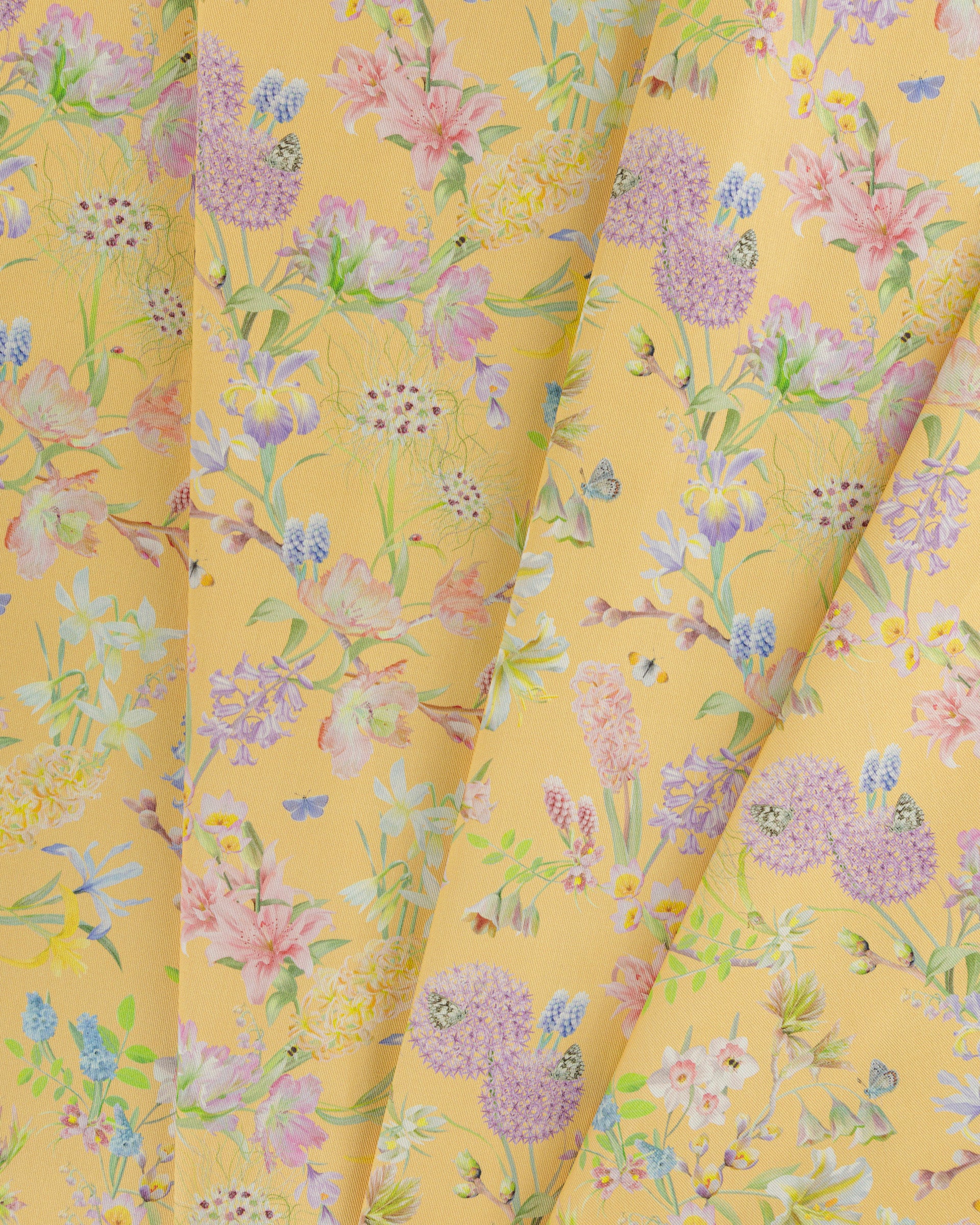 Draped Hopeful Beginnings cotton twill furnishing fabric in yellow showing detailed botanical floral pattern.