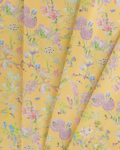 Draped Hopeful Beginnings cotton twill furnishing fabric in yellow showing detailed botanical floral pattern.