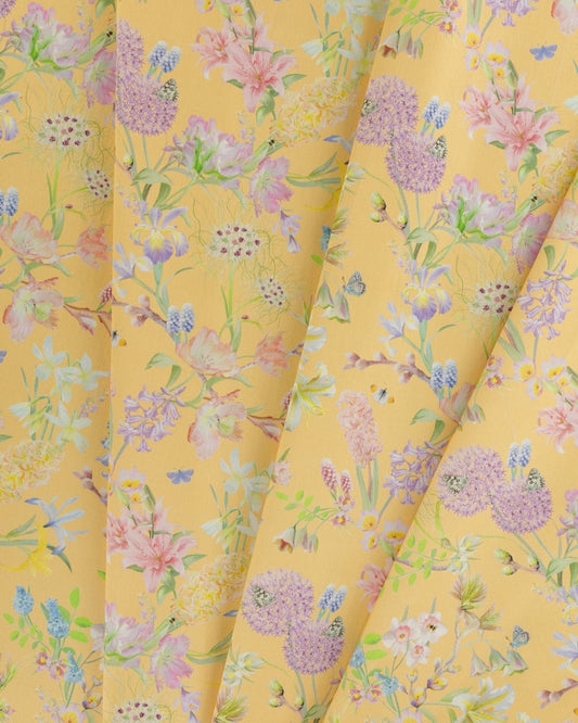 Draped Hopeful Beginnings cotton twill furnishing fabric in yellow showing detailed botanical floral pattern.