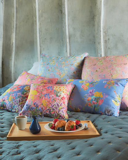Soothing bedroom interior filled with sustainable pink and blue cushions and soft furnishings in floral patterned fabrics