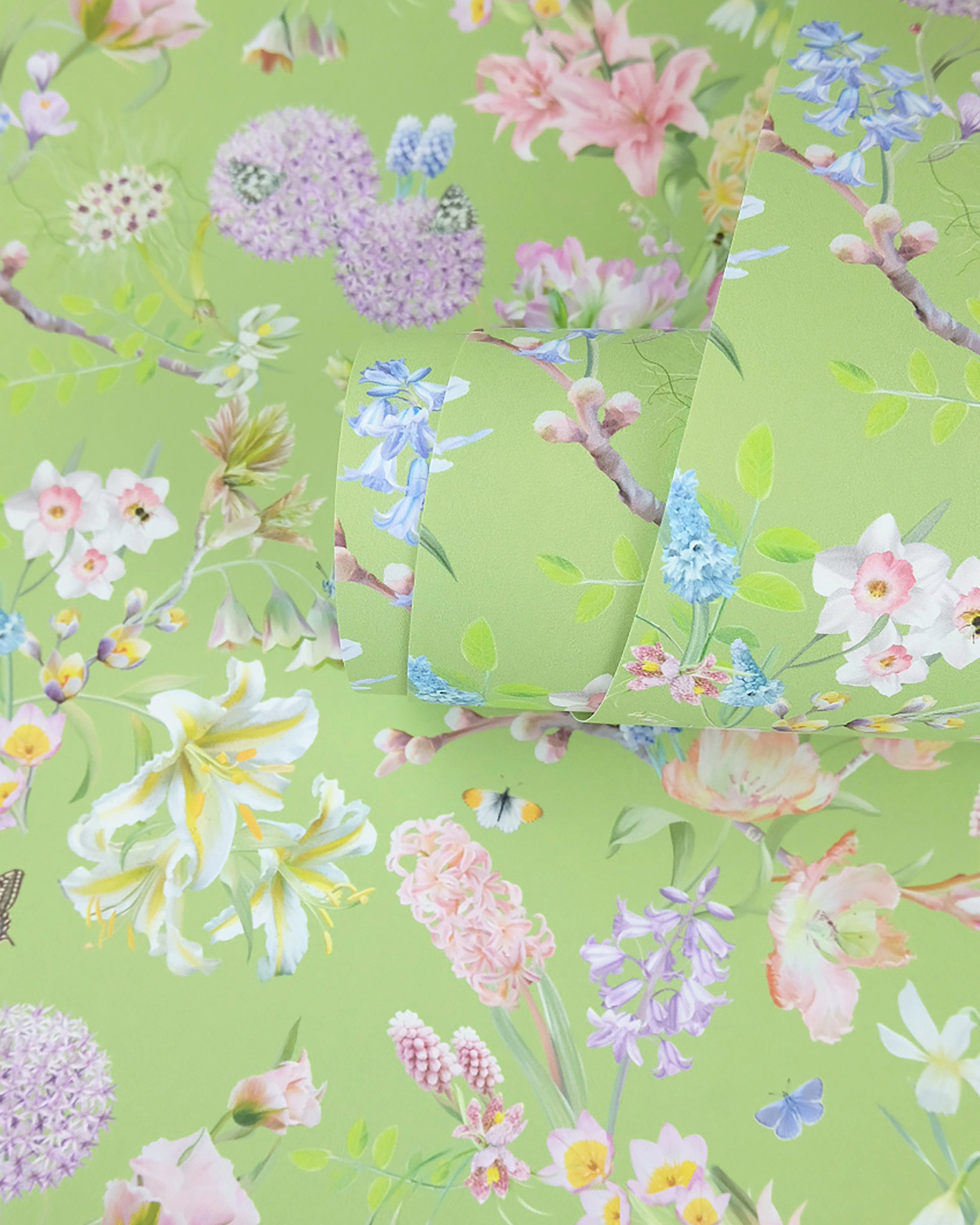 A roll of soft green neutral wallpaper with a spring botanical print for traditional cottage interior design