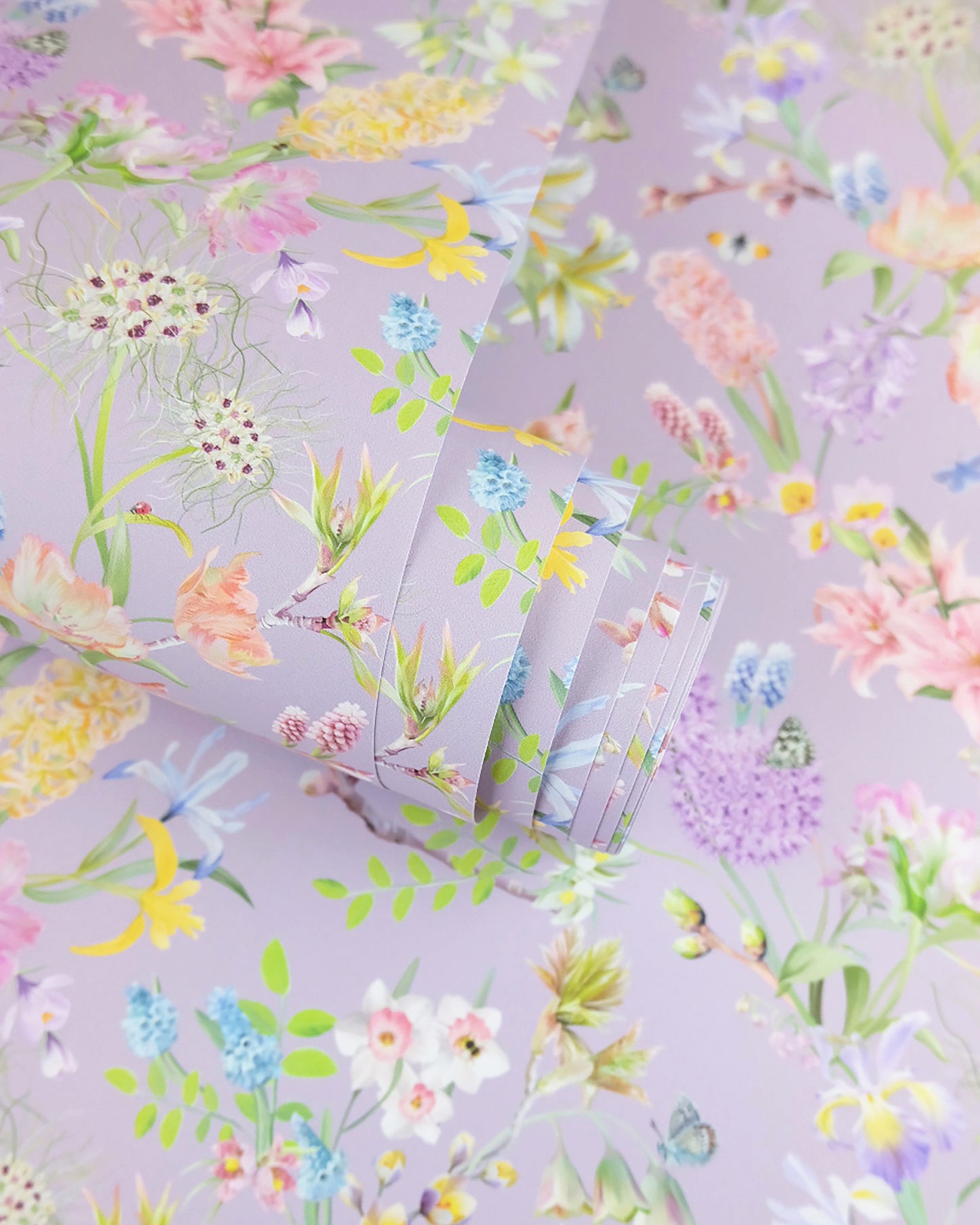 A roll of soft purple neutral wallpaper with a spring botanical print for colourful interior design inspiration