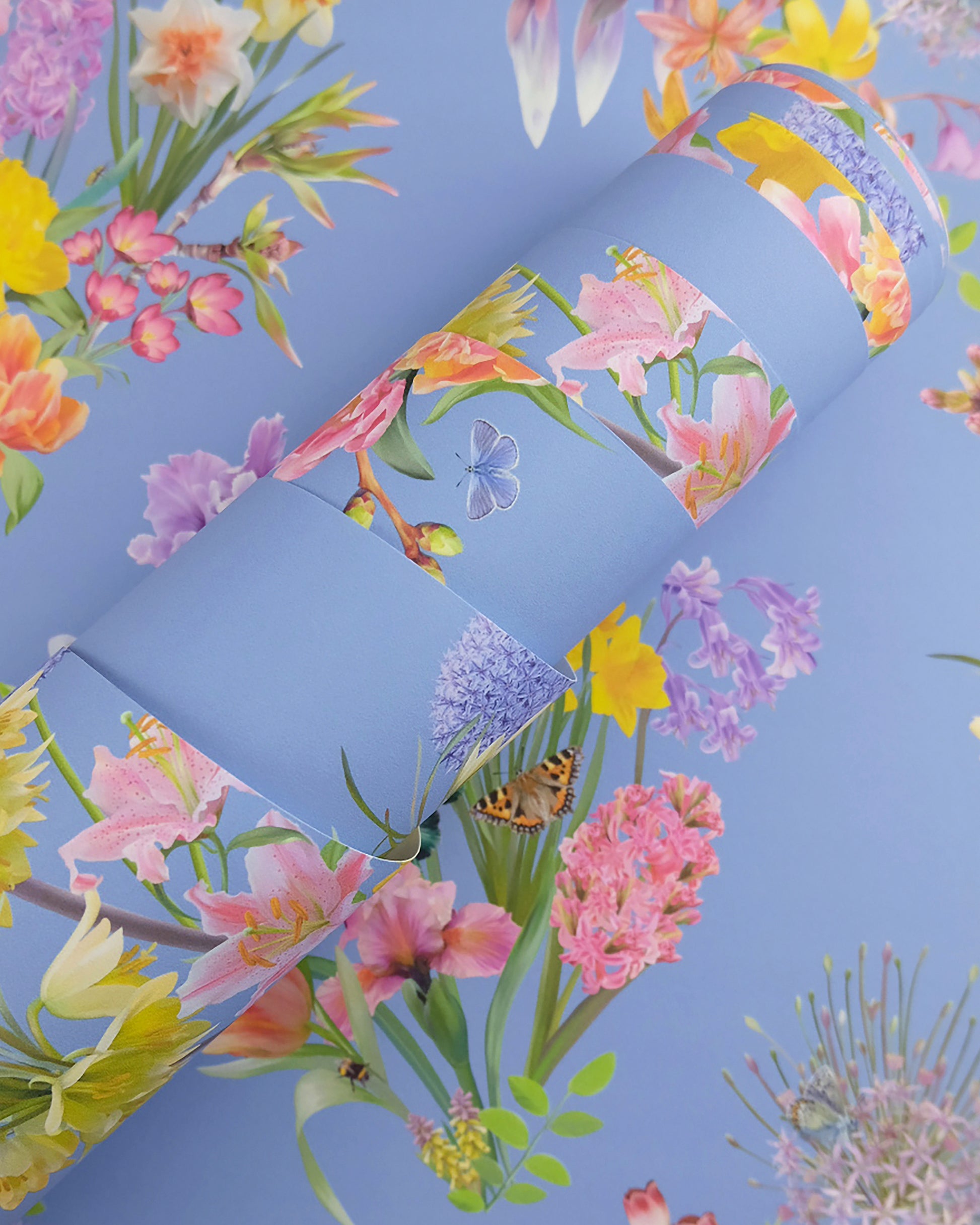A roll of maximalist designer wall covering in bright blue with a spring botanical print for modern interiors