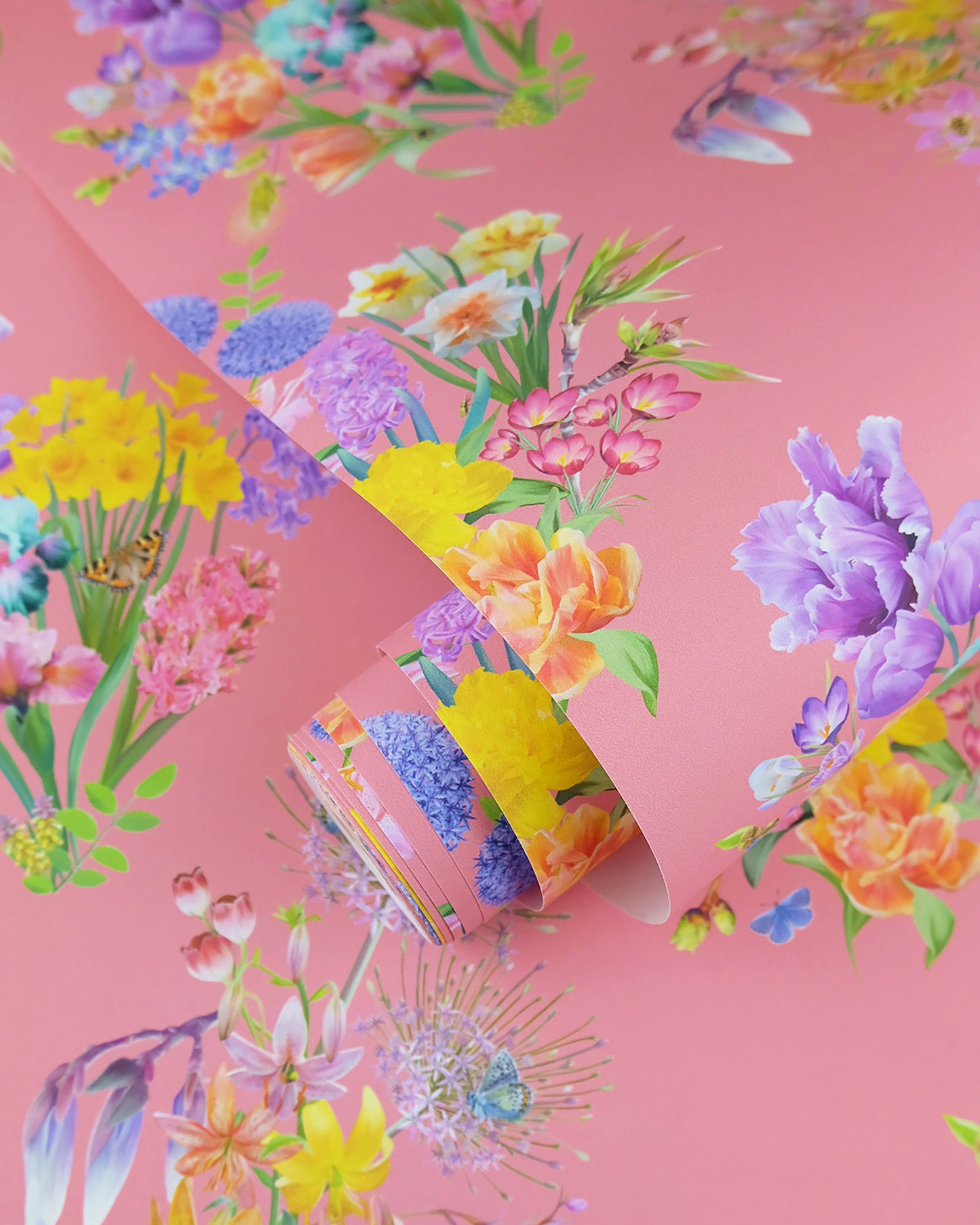 A roll of maximalist designer wall covering in bubblegum pink with a summer botanical print for contemporary interiors